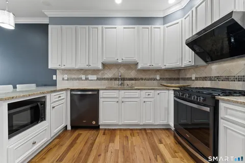 a kitchen with stainless steel appliances granite countertop a stove and white cabinets