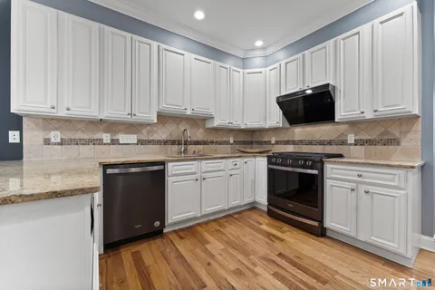 a kitchen with granite countertop white cabinets and stainless steel appliances