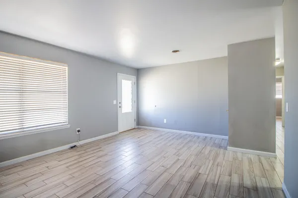 a view of an empty room with wooden floor and a window