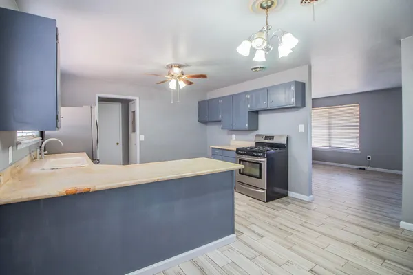 a large kitchen with stainless steel appliances a large counter top a sink a stove and a refrigerator