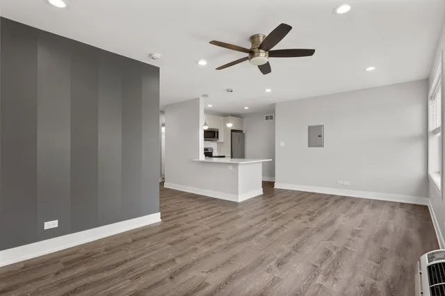 a view of a livingroom with a ceiling fan & wooden floor