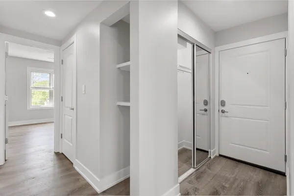 an empty room with wooden floor closet and windows