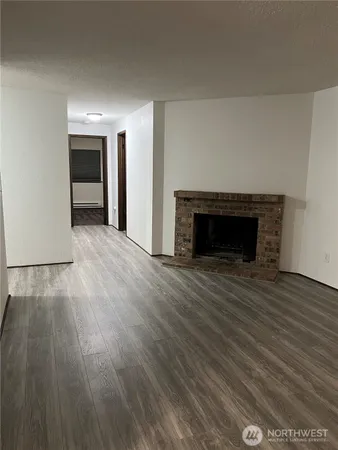 an empty room with wooden floor fireplace and windows