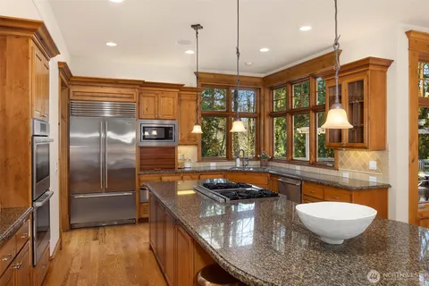 a kitchen with stainless steel appliances granite countertop a stove a refrigerator and a wooden cabinets