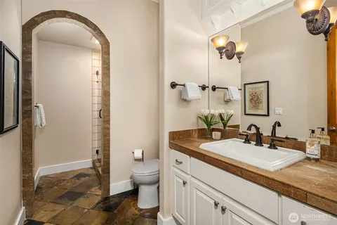 a bathroom with a granite countertop sink a toilet and a mirror