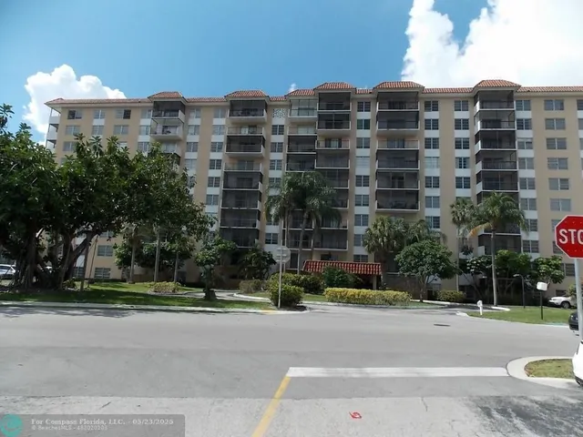 a front view of multi story residential apartment building with yard and traffic signal
