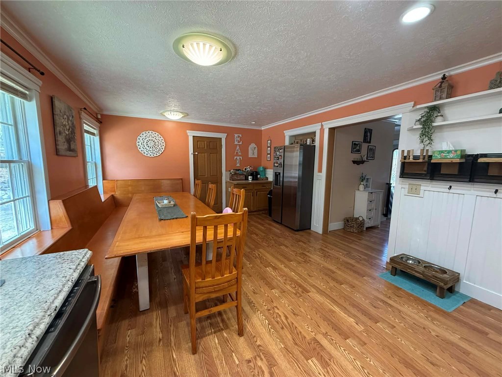 7170 Old Town Road Mount Perry, OH 43760 - Photo 7 of 41 Dining area with light wood-style floors, ornamental molding, and a textured ceiling