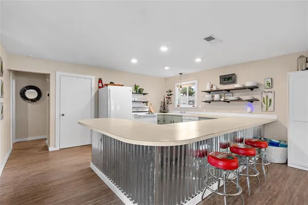 a kitchen with stainless steel appliances granite countertop a sink dishwasher and a refrigerator with wooden floor