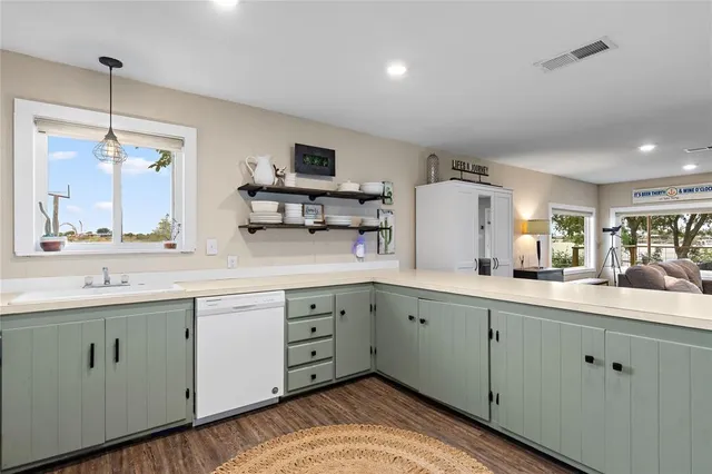 a kitchen with a sink dishwasher and white cabinets with wooden floor