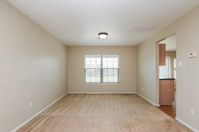 an empty room with chandelier fan and windows