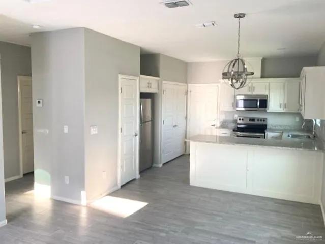 a view of a kitchen with granite countertop stainless steel appliances and a chandelier