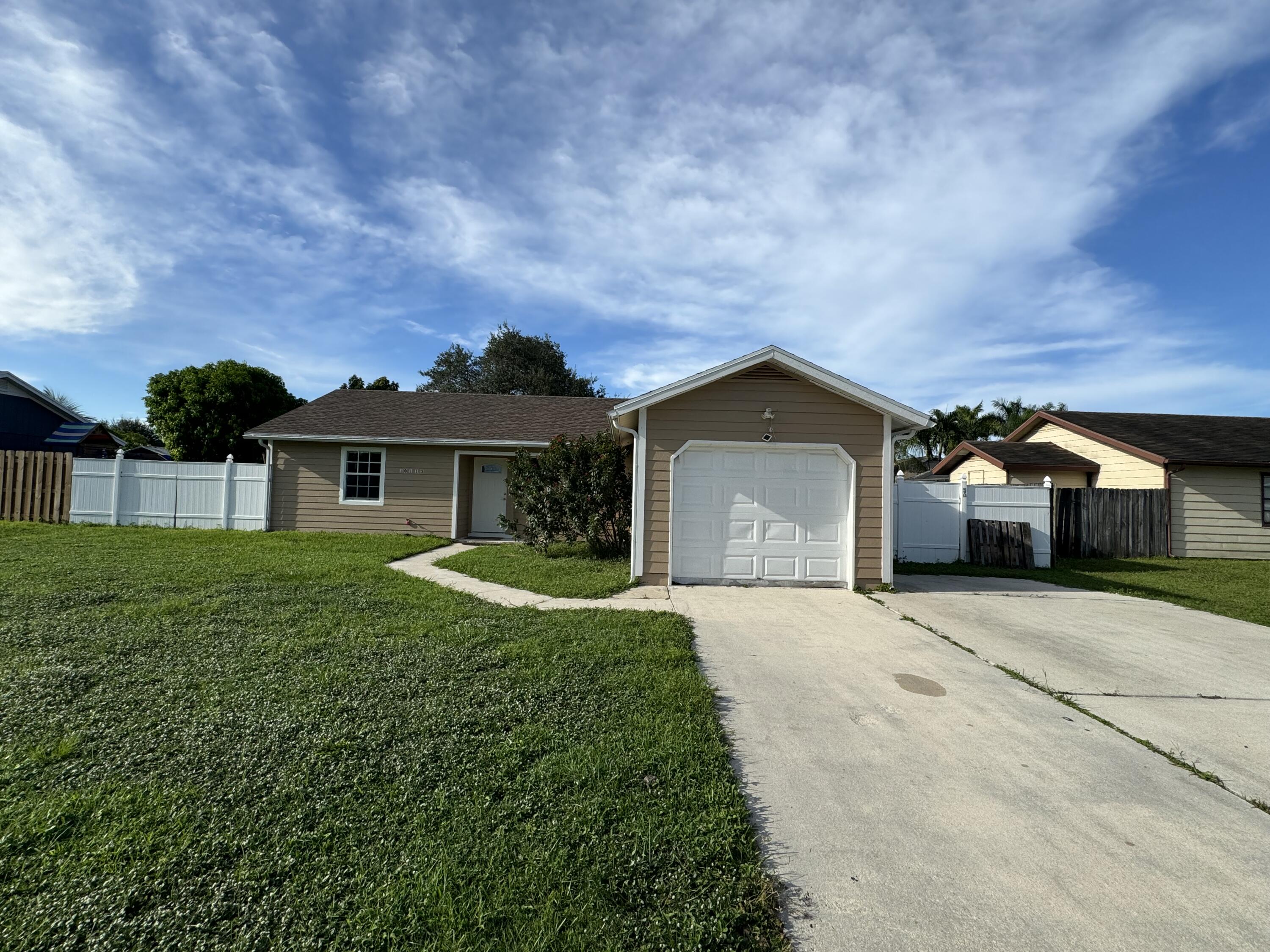 10115 Patience Lane Royal Palm Beach, FL 33411 - Photo 1 of 8 a front view of a house with a yard and garage