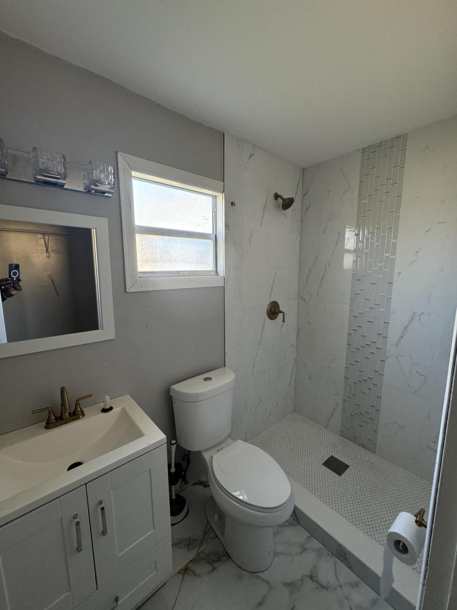 10115 Patience Lane Royal Palm Beach, FL 33411 - Photo 3 of 8 a bathroom with a toilet a sink a mirror and shower