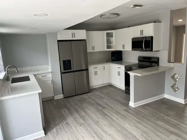 a kitchen with a sink a microwave a refrigerator and cabinets