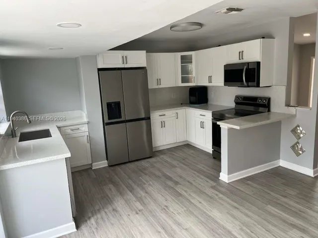 a kitchen with a sink a microwave a refrigerator and cabinets