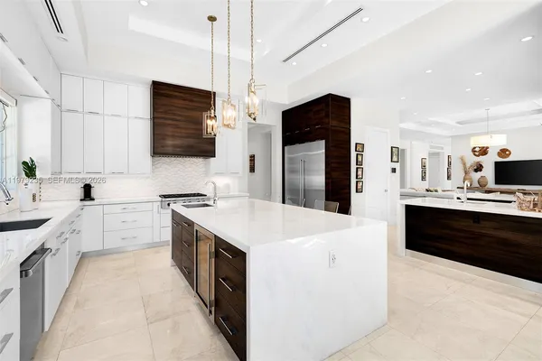 a large white kitchen with a stove top oven a sink dishwasher and a refrigerator with wooden floor