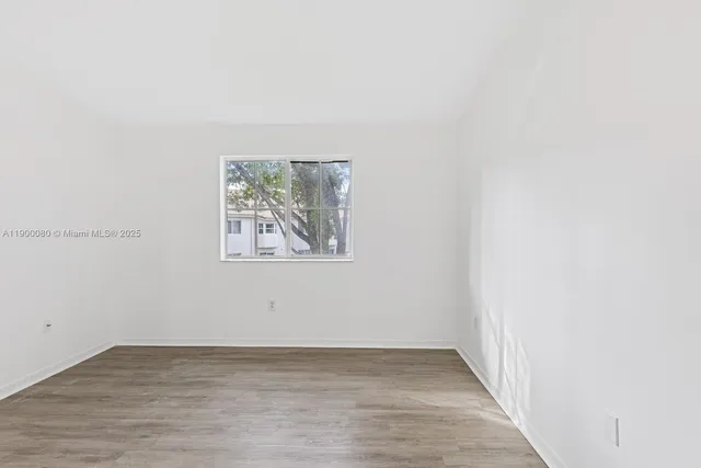 an empty room with wooden floor and window