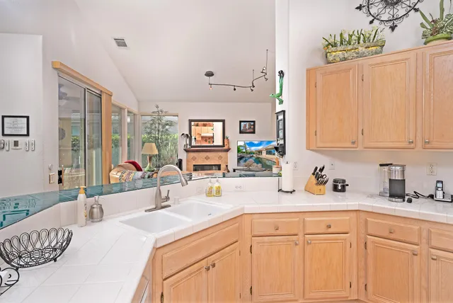 a kitchen with a sink dishwasher and white cabinets with wooden floor