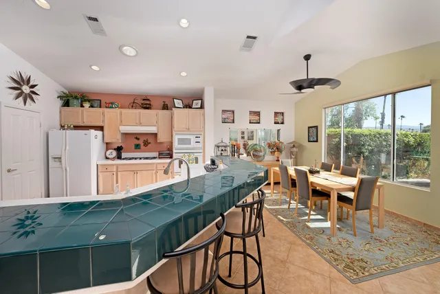 a view of a dining room and livingroom with furniture wooden floor a rug a fireplace and a large window