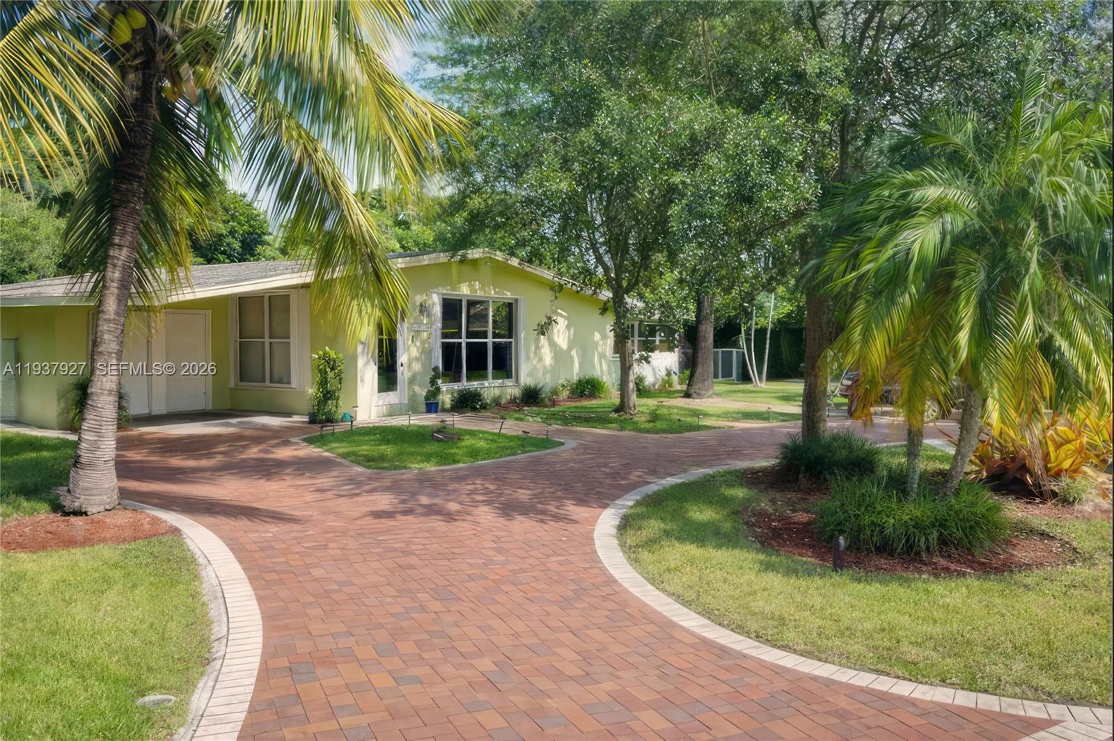 12501 Southwest 90th Avenue Miami, FL 33176 - Photo 4 of 27 a view of a white house with a small yard plants and palm trees