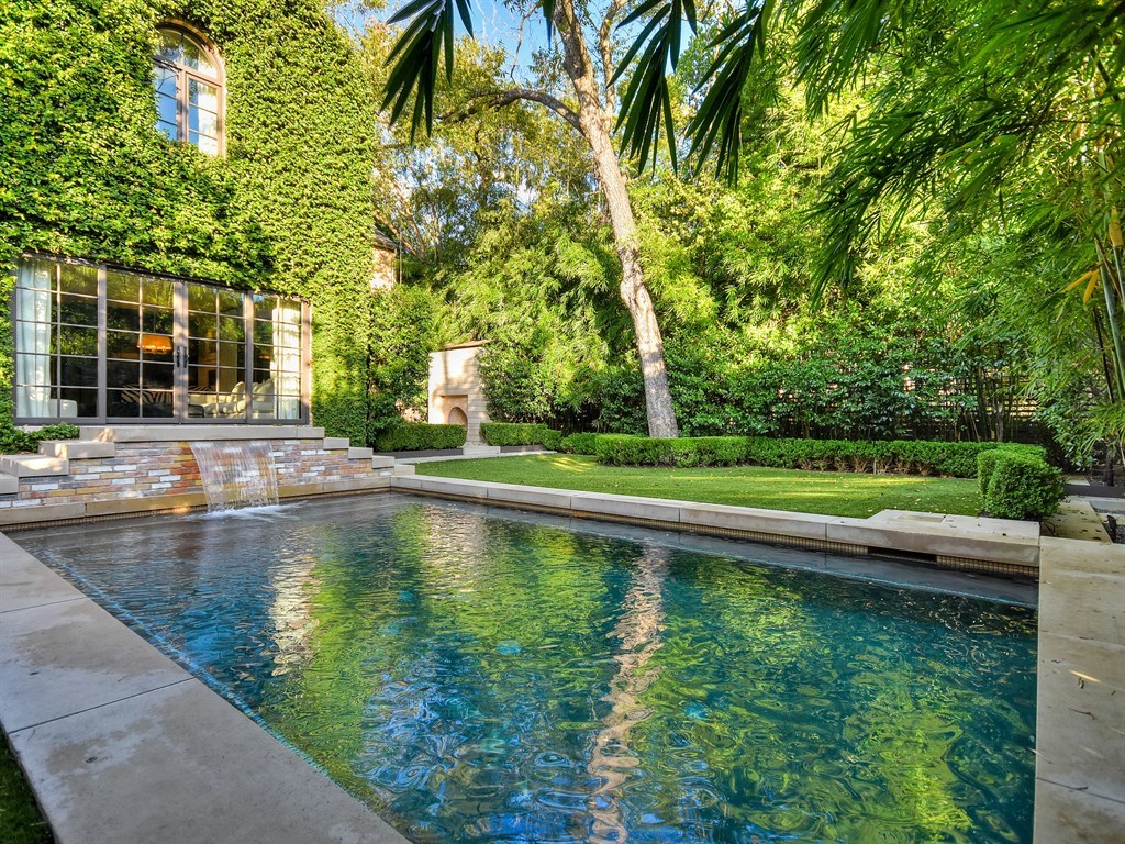 a view of pool with a yard and large trees
