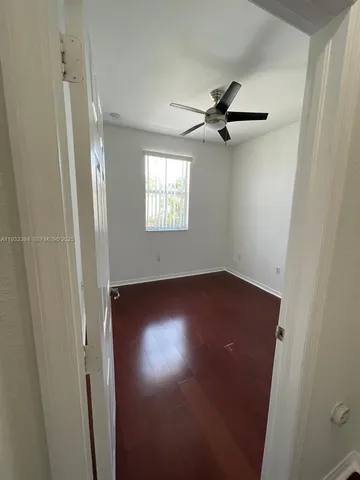 an empty room with windows and a ceiling fan