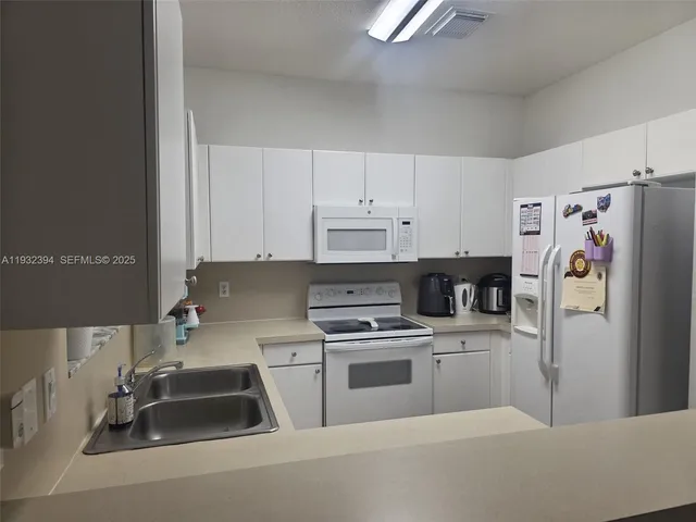 a kitchen with a refrigerator a stove a sink and white cabinets