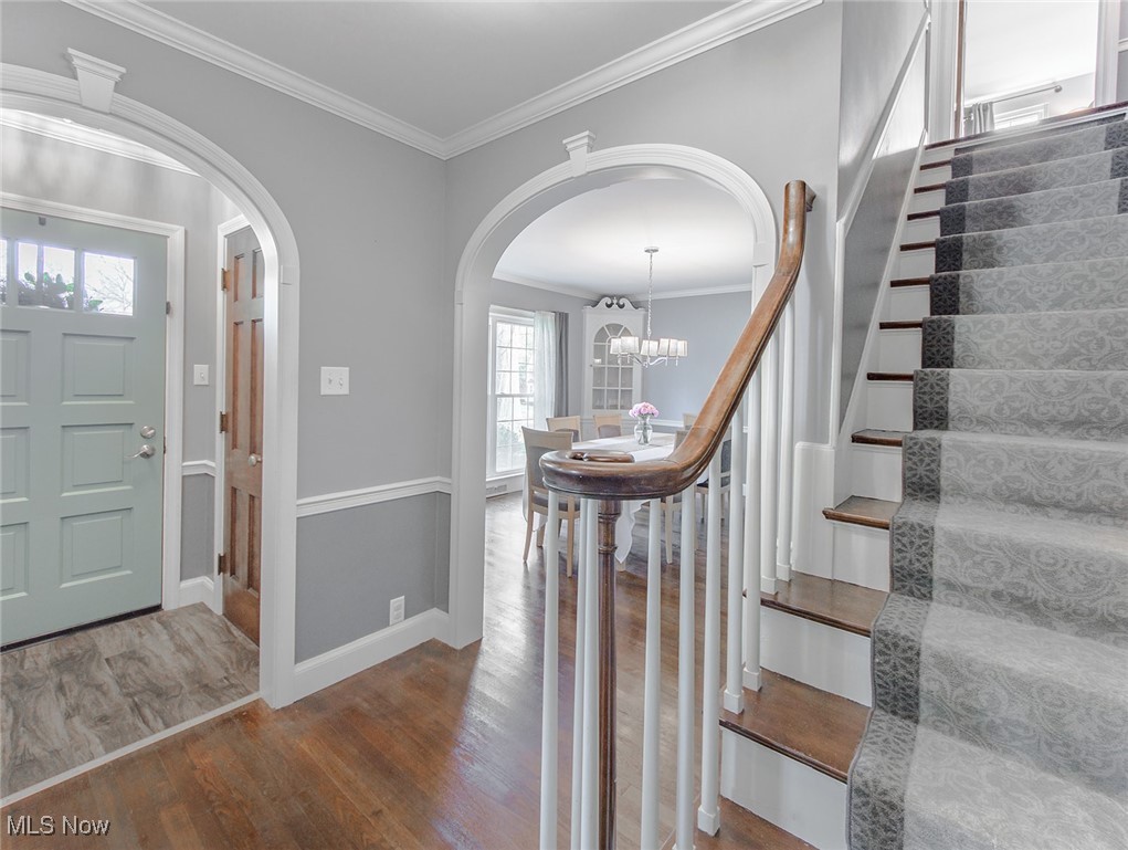 754 Merriman Road Akron, OH 44303 - Photo 6 of 41 Once inside the foyer opens to a grand hallway. Notice the curve of the newel post, the many arches, the crown moldings and trimwork, and the original hardwood floors. A glimpse into the dining room is shown.