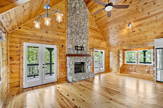 a view of an empty room with wooden floor fireplace and a window