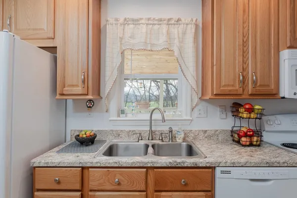 a kitchen with granite countertop stainless steel appliances white cabinets and a sink