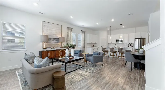 a living room with furniture kitchen view and a wooden floor