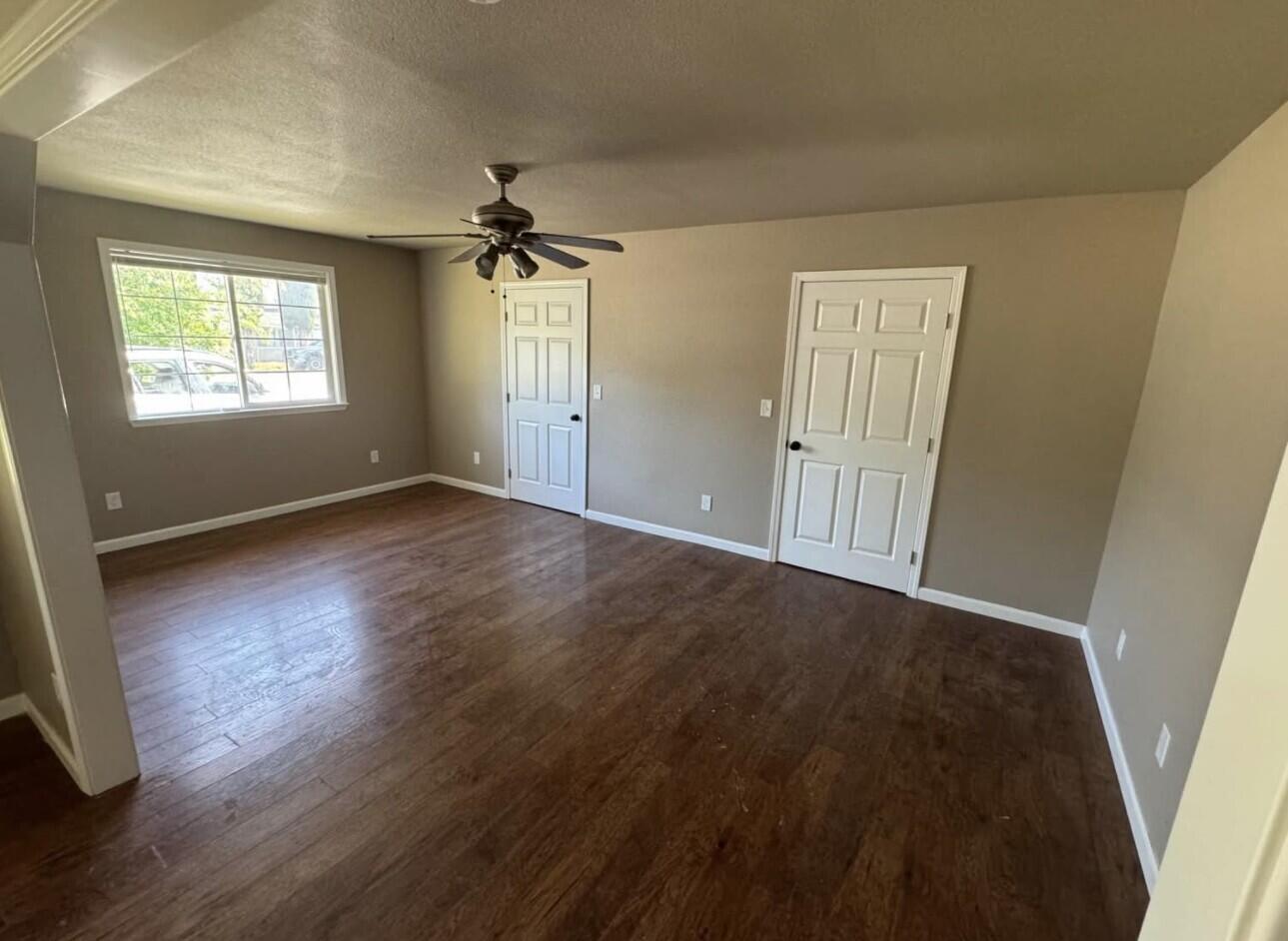 566 Roundup Avenue Red Bluff, CA 96080 - Photo 14 of 16 an empty room with wooden floor ceiling fan and windows