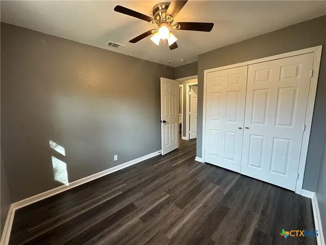 a view of an empty room with window and a ceiling fan
