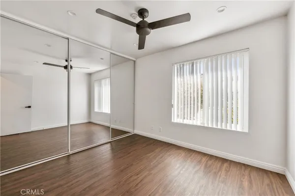 a view of empty room with wooden floor and ceiling fan