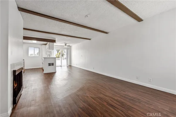 an empty room with wooden floor fireplace and windows