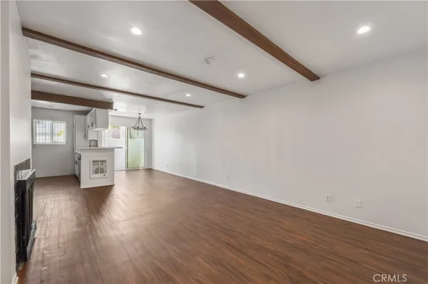an empty room with wooden floor fireplace and windows