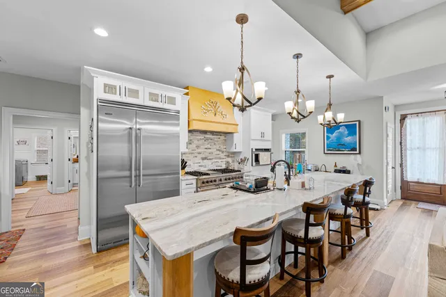 a kitchen with stainless steel appliances kitchen island granite countertop a table chairs and a refrigerator
