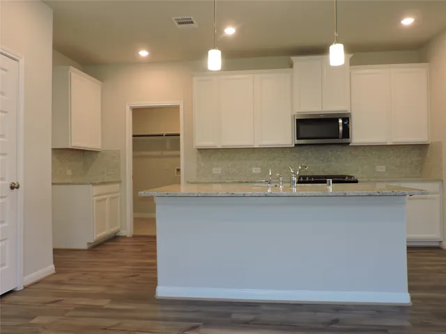 a kitchen with kitchen island white cabinets and stainless steel appliances
