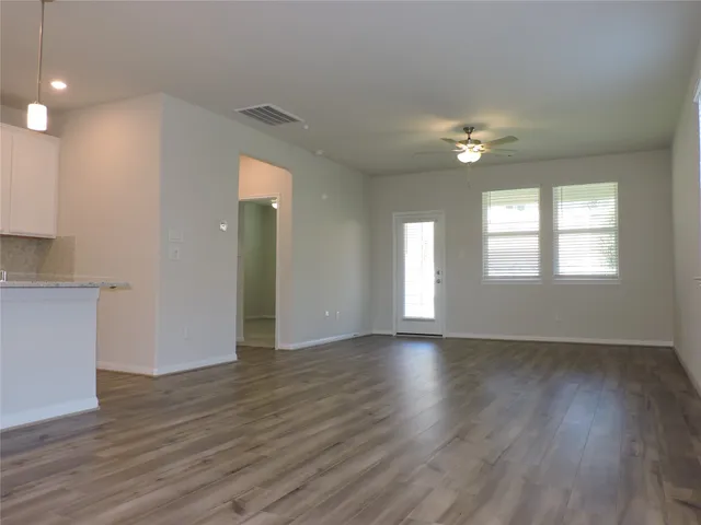 an empty room with wooden floor and windows