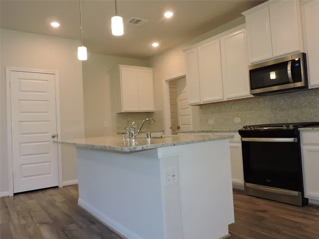 a kitchen with kitchen island granite countertop a stove and a sink
