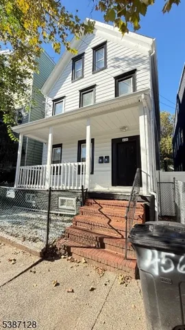 a view of a white house with large windows next to a yard