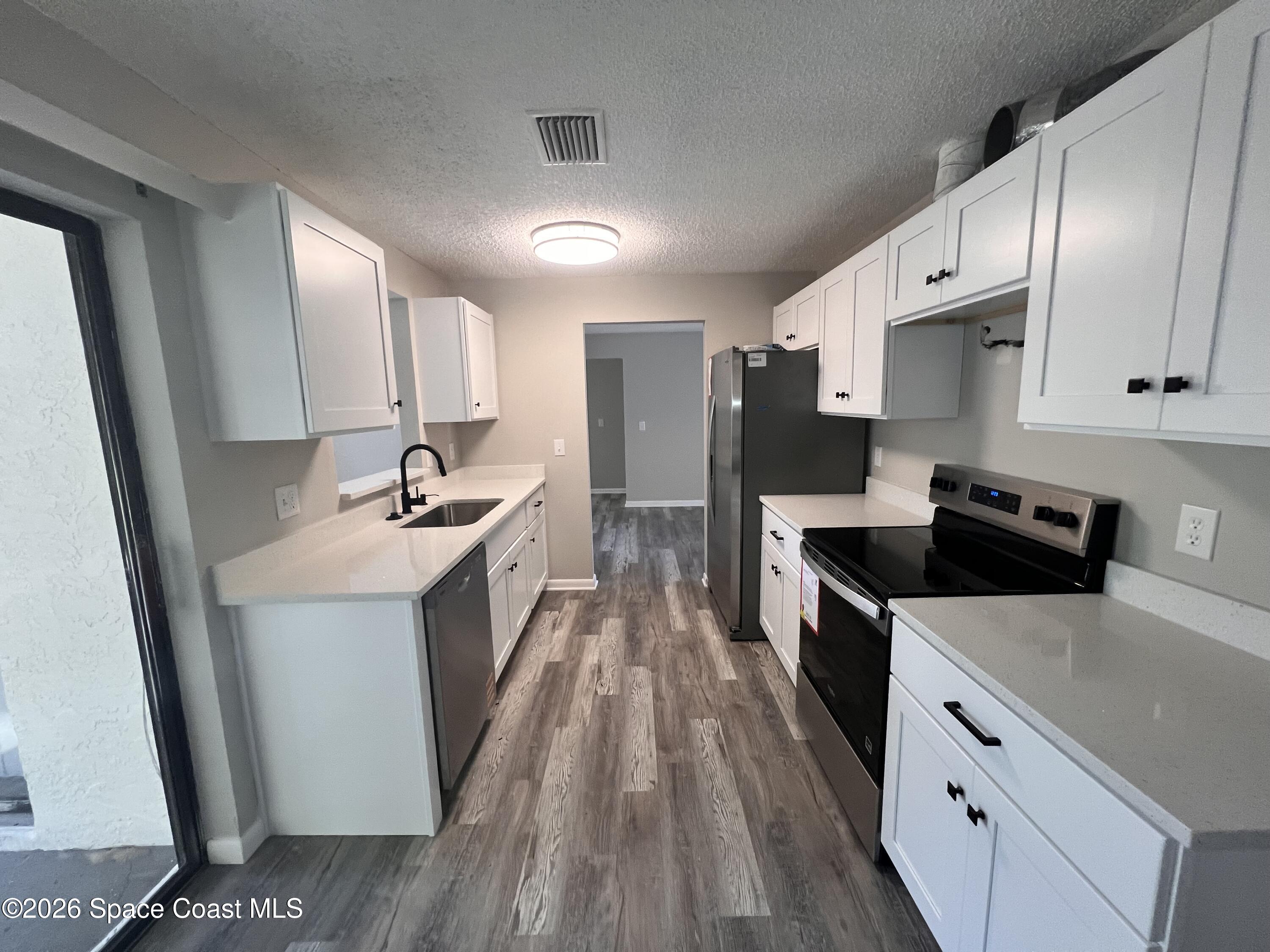 1456 Reed Street Northwest Palm Bay, FL 32907 - Photo 8 of 19 a large kitchen with stainless steel appliances a sink stove and refrigerator