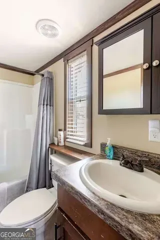 a en suite bathroom with a granite countertop sink and a large mirror