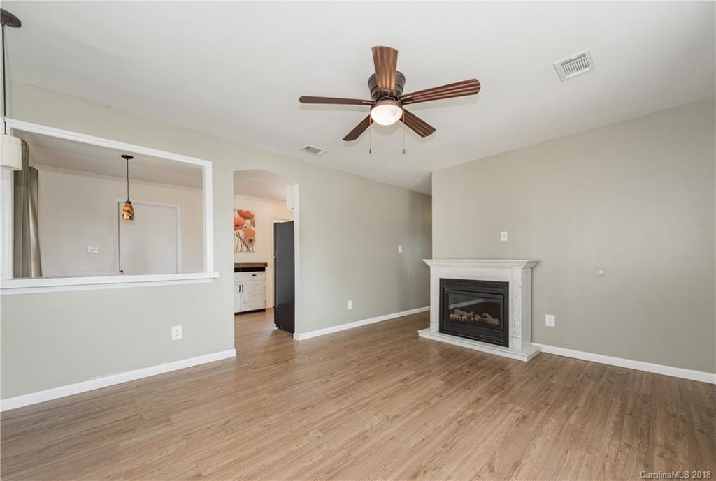 8002 Wynnview Road Indian Trail, NC 28079 - Photo 4 of 24 an empty room with wooden floor a fireplace and windows