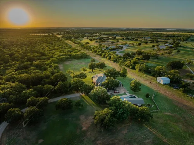an aerial view of residential houses with outdoor space and trees