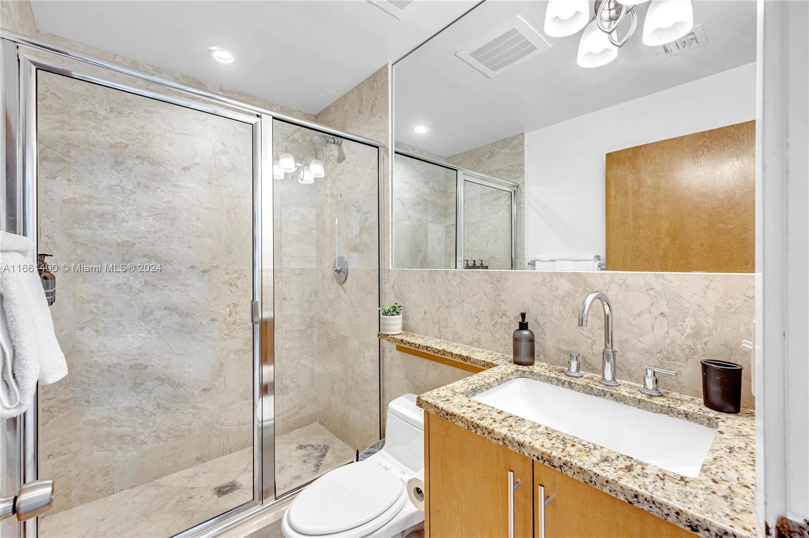 7939 East Drive, Unit 13 North Bay Village, FL 33141 - Photo 11 of 31 a bathroom with a granite countertop sink toilet mirror and shower