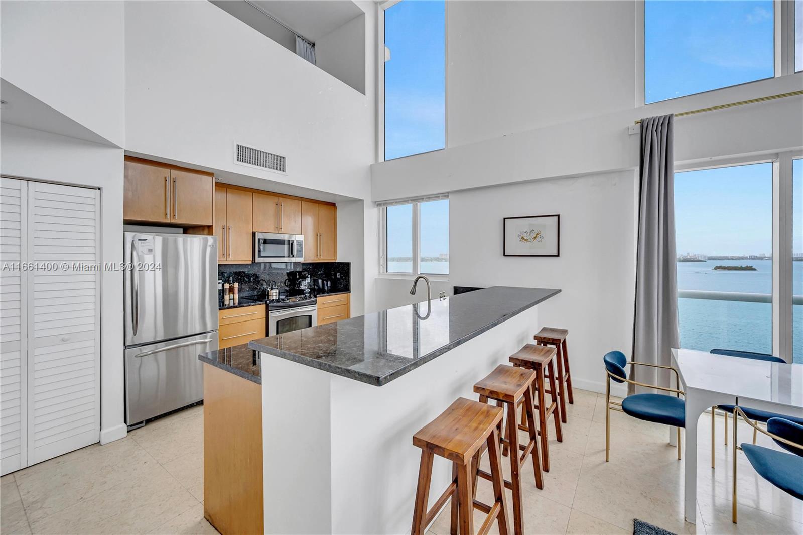 7939 East Drive, Unit 13 North Bay Village, FL 33141 - Photo 22 of 31 a kitchen with stainless steel appliances granite countertop a refrigerator a stove a sink a dining table and chairs
