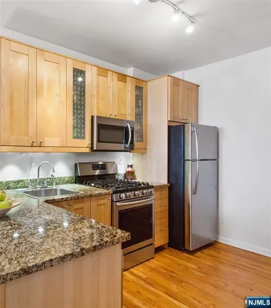 a kitchen with granite countertop a refrigerator stove top oven and sink