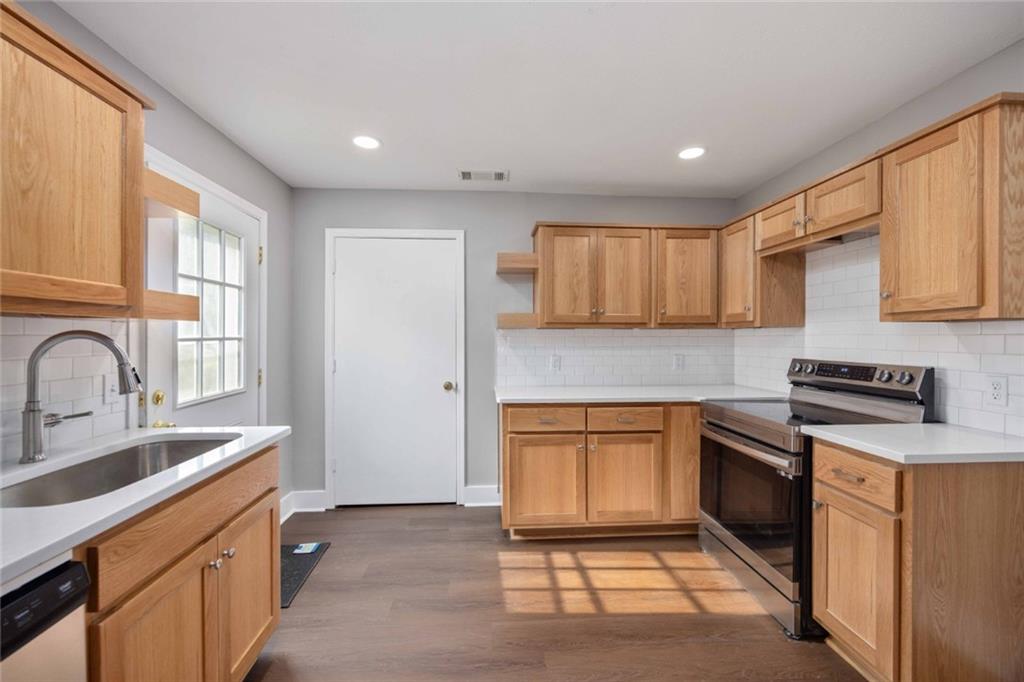 9 Spies Road Fort Mitchell, AL 36856 - Photo 10 of 23 Kitchen featuring wood-finish cabinetry, white countertops, a subway tile backsplash, stainless steel appliances, and wood-finish flooring