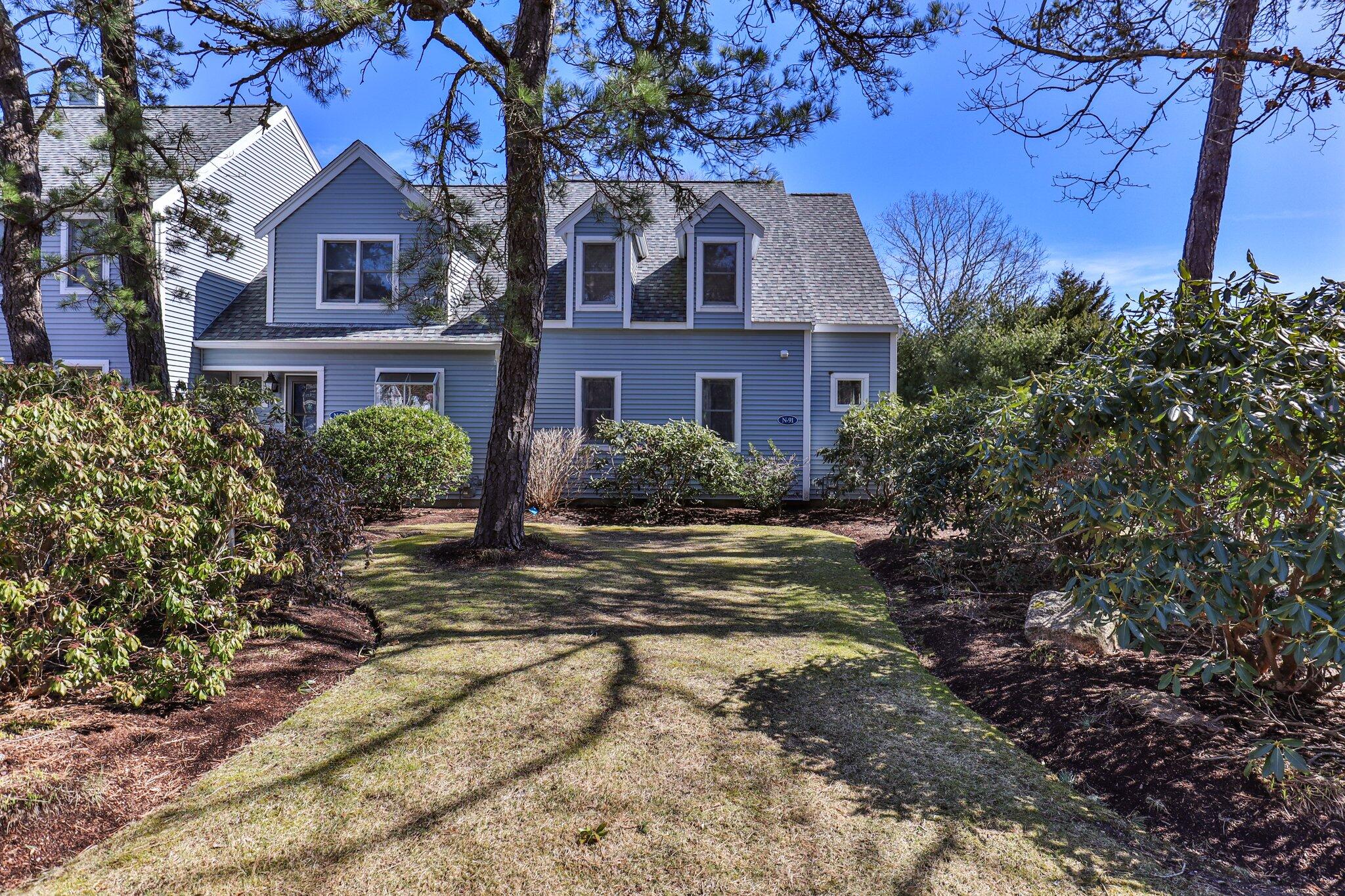 91 Shellback Way, Unit N Mashpee, MA 02649 - Photo 29 of 40 a view of a brick house next to a yard with large trees